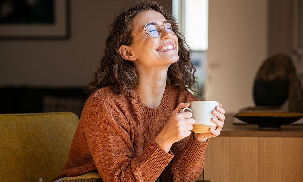 Young woman smiling while having her cup of coffee.