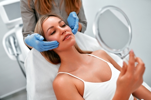 woman looking at her face at a medical spa after treatment